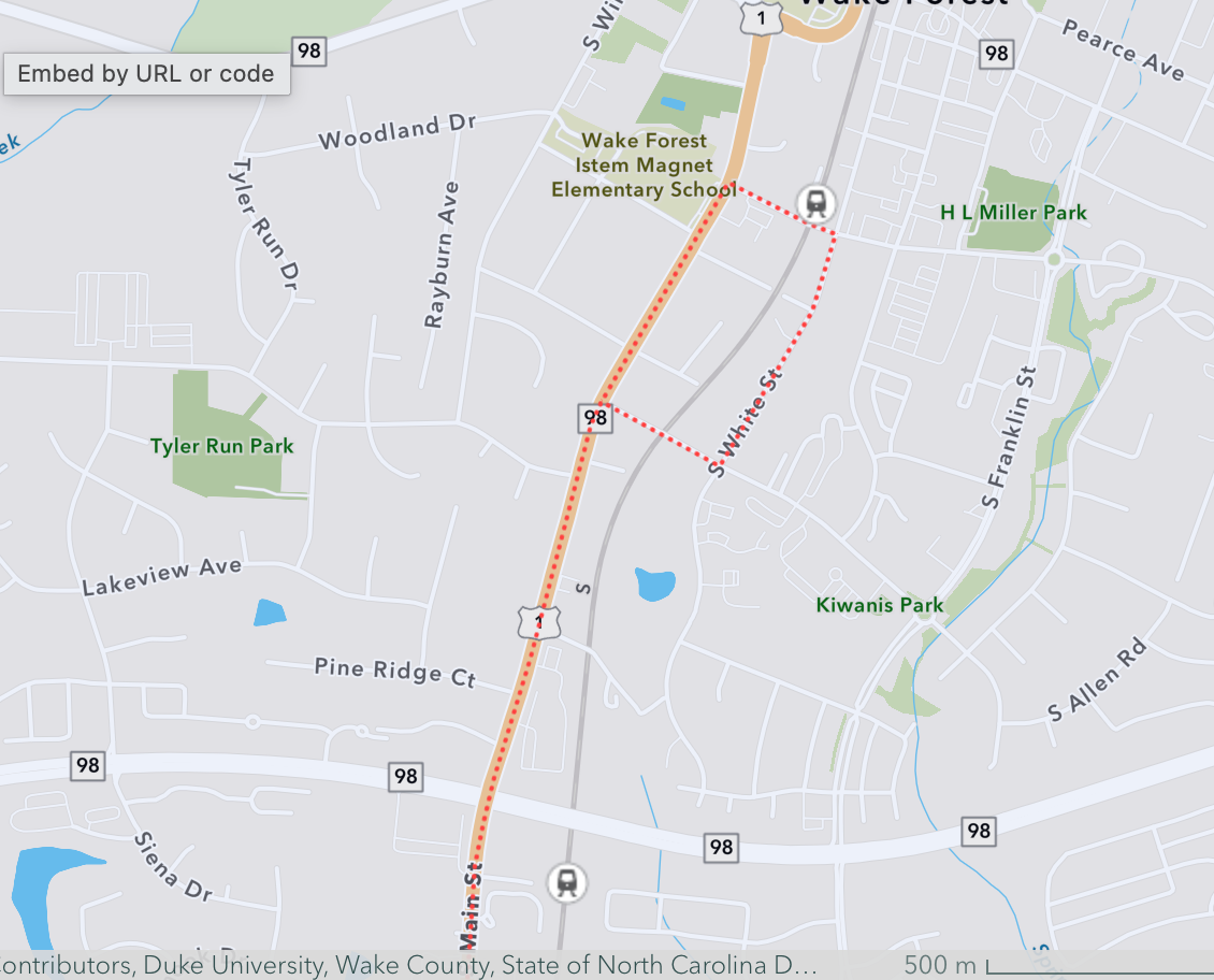  Digital street map of Wake Forest, NC, displaying the S-Line rail route as a dotted orange line. The map highlights the rail line's path past key landmarks like the Wake Forest iSTEM Magnet Elementary School and its close alignment with South Main Street