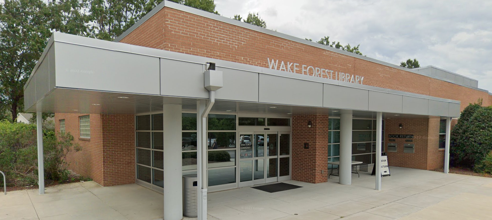 The main entrance of the Wake Forest Library, a brick building with a large metal canopy, glass doors, and a "BOOK RETURN" slot. The main entrance of the Wake Forest Library, a brick building with a large metal canopy, glass doors, and a "BOOK RETURN" slot.