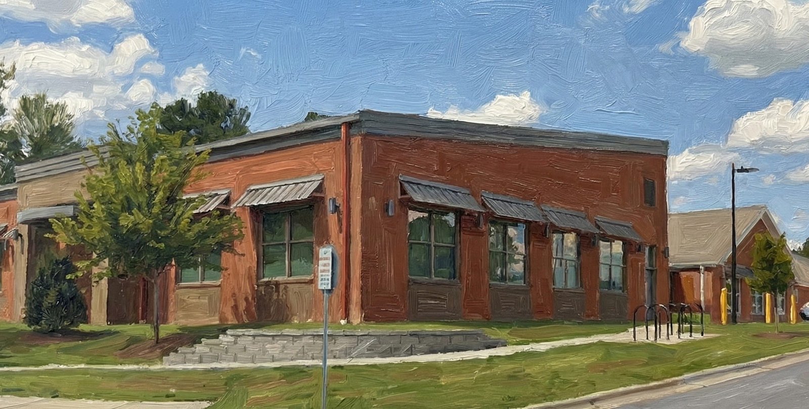 painting of the Wake Forest Center for Active Aging. The single-story red brick building is depicted with thick, expressive brushstrokes under a bright blue sky with white clouds. A water tower is visible in the upper left background, and cars are parked in a lot to the right. Green trees and a grassy lawn frame the foreground.